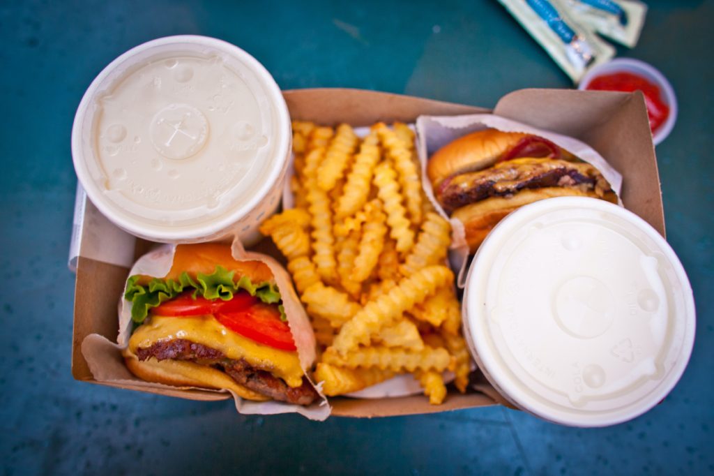 Photo of two milkshakes, burger, and fries